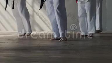 特写镜头。 一群青少年一起同步训练武术.. 光着脚，白色和服。 男女青少年